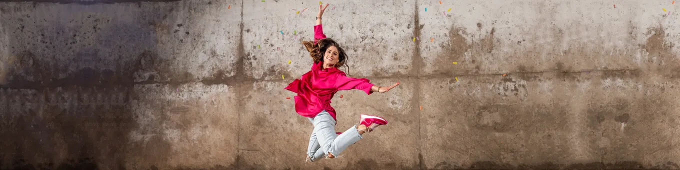Glückliche springende Frau mit H-Pinky magenta pink